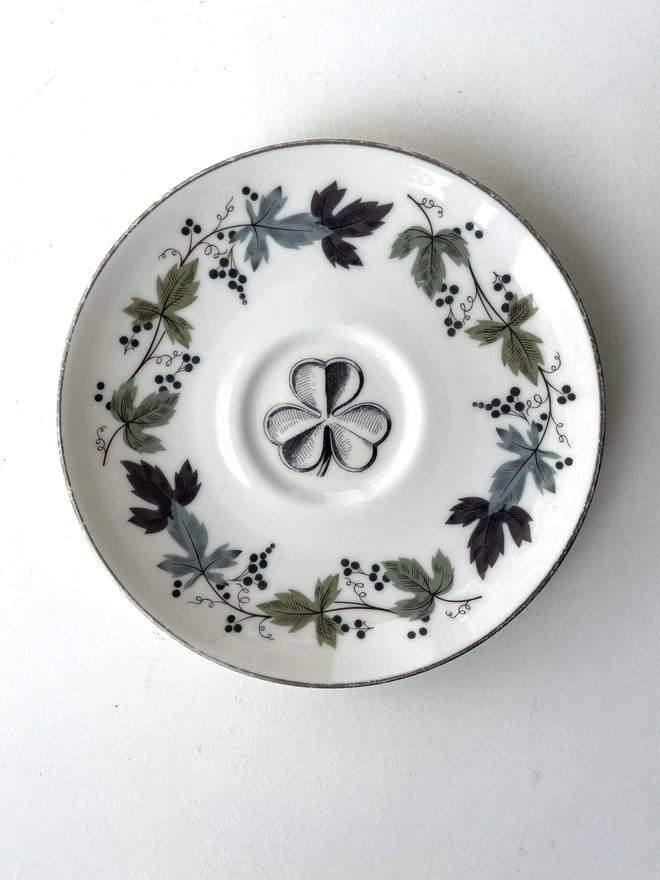 vintage plate with ornate border has a black and white image of a victorian lucky irish shamrock in the centre