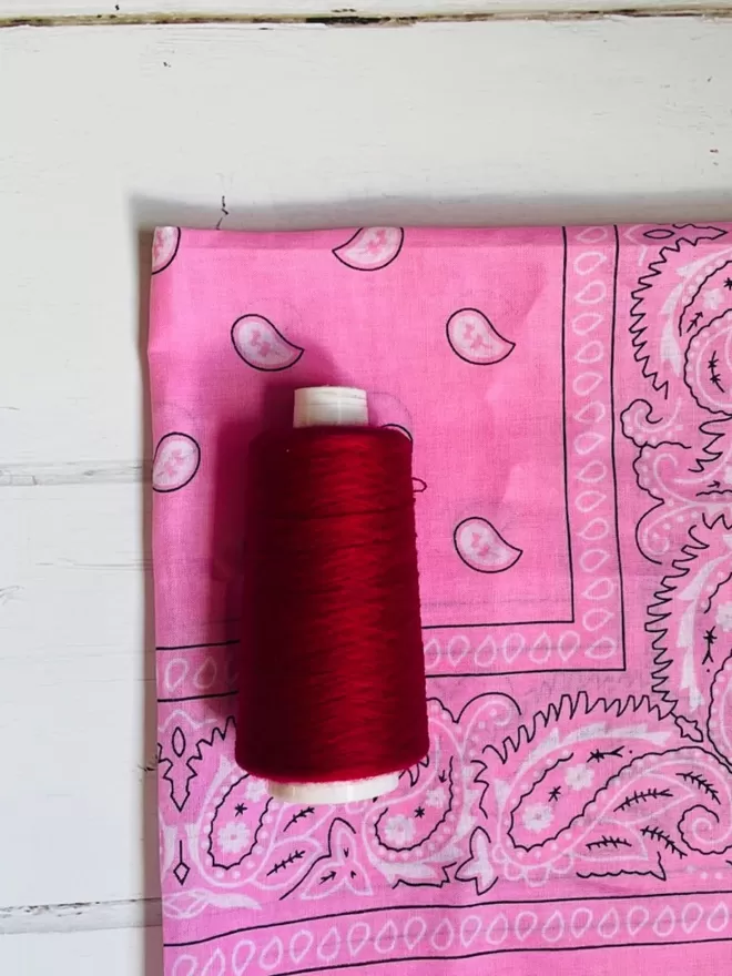 Pink bandana with red thread.