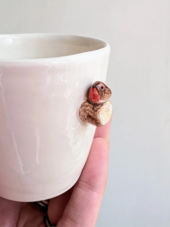 white espresso coffee cup with tiny robin red breast bird on a ceramic tree branch