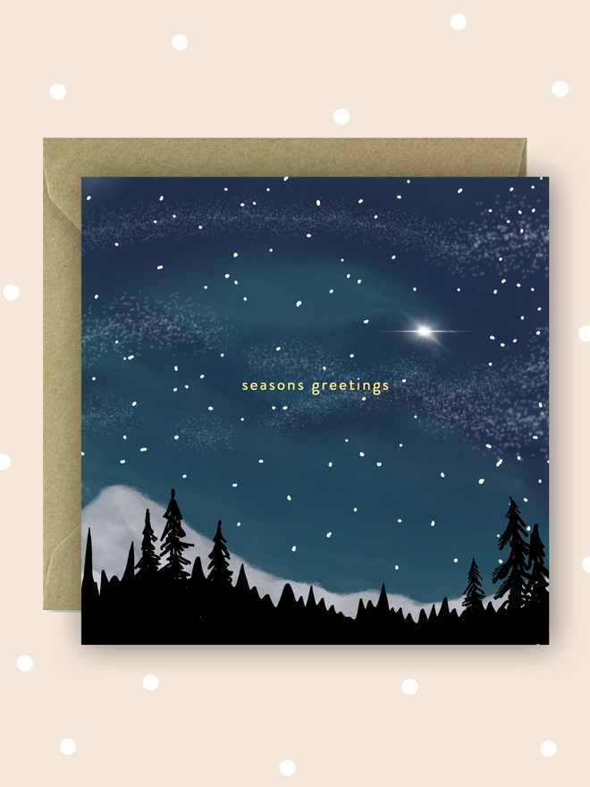 Seasons Greetings Christmas card. Starry night sky scene with snowy mountains and outlines of trees. 