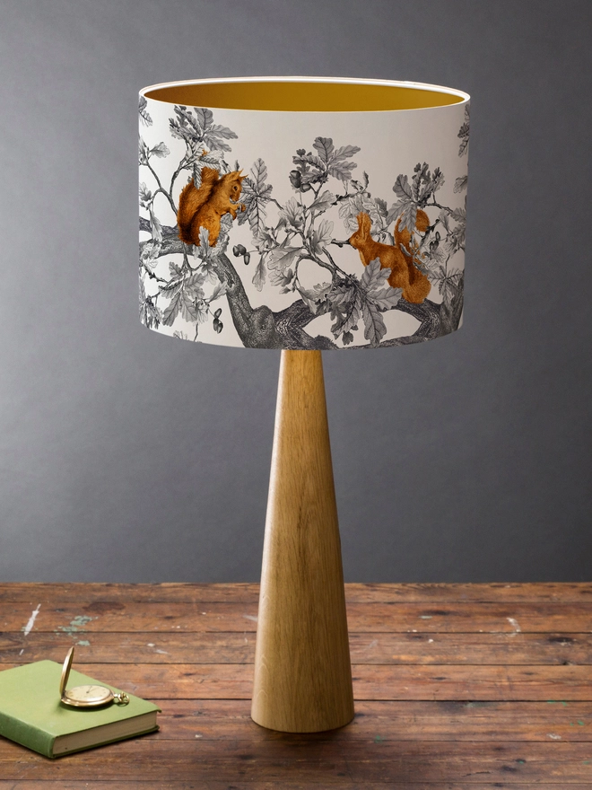 A decorative lampshade featuring red squirrels among oak leaves and acorns, inspired by the British countryside and woodland wildlife.