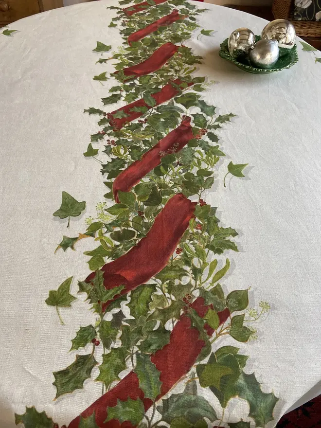 christmas garland centrepiece tablecloth. a white tablecloth emblazoned with a christmas garland on a table.