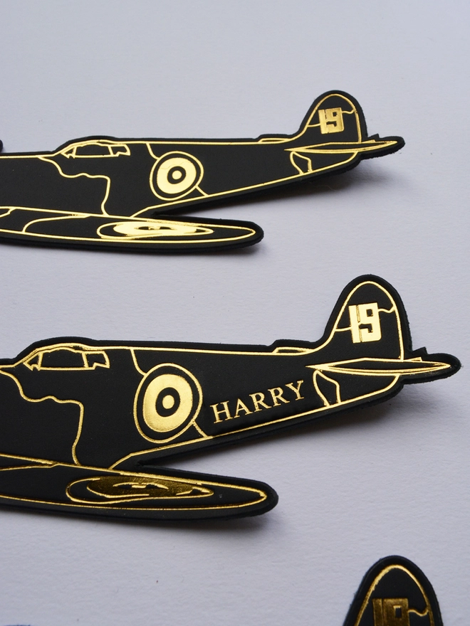 detail of personalisation in gold on a black leather spitfire shaped airplane bookmark by natthakur