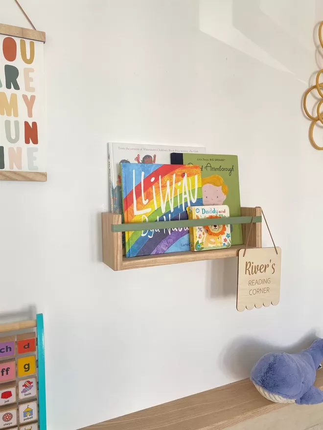 Solid wood bookshelf filled with colourful children’s books and bespoke kids flag