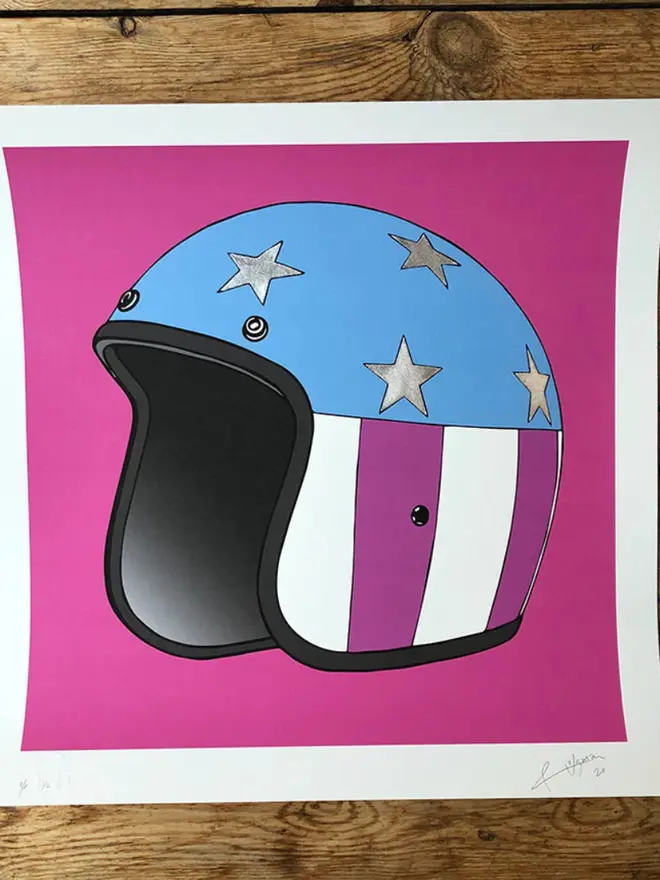 Motor cycle helmet with a star-and-stripe design on a pink background. 
