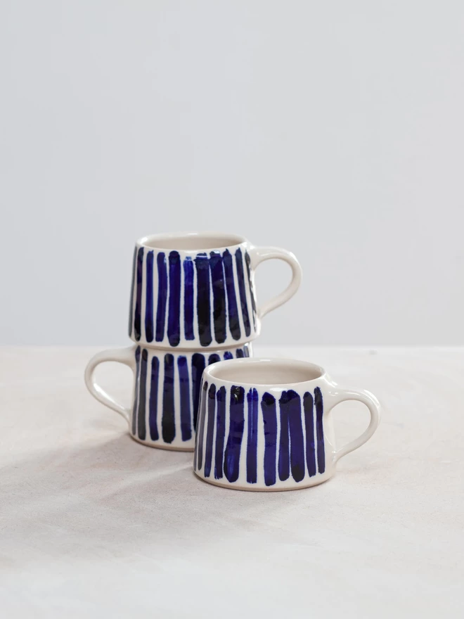 Set of three stacked handmade ceramic mugs with cobalt blue hand-painted stripes