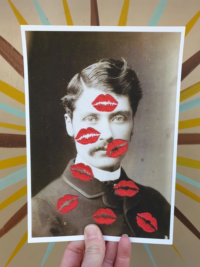 B&W photo print of man covered in embroidered red kisses held against coloured background 