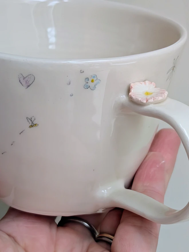 handmade ceramic cup for mum with flowers, daisy hearts and tiny honey bee in white earthenware with pink highlights