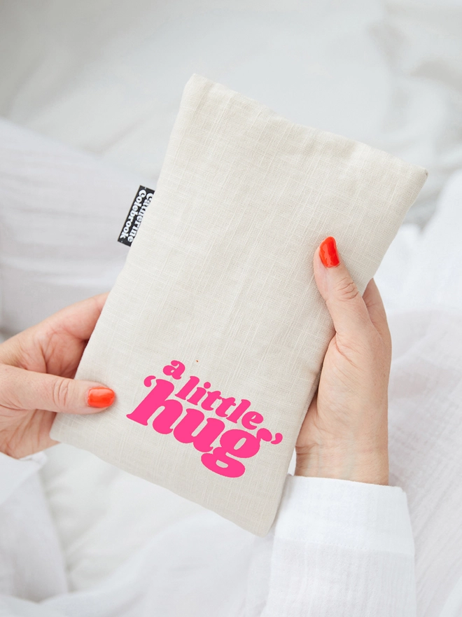 Catherine Colebrook natural linen cute hot water bottle with neon pink 'a little hug' text