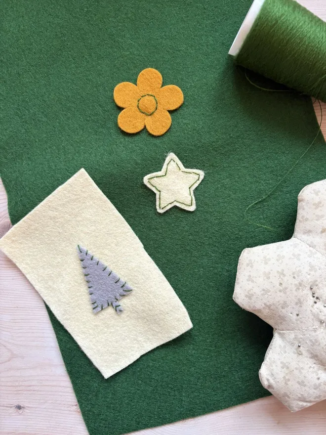 Felt shapes sewn on some green felt with embroidery thread