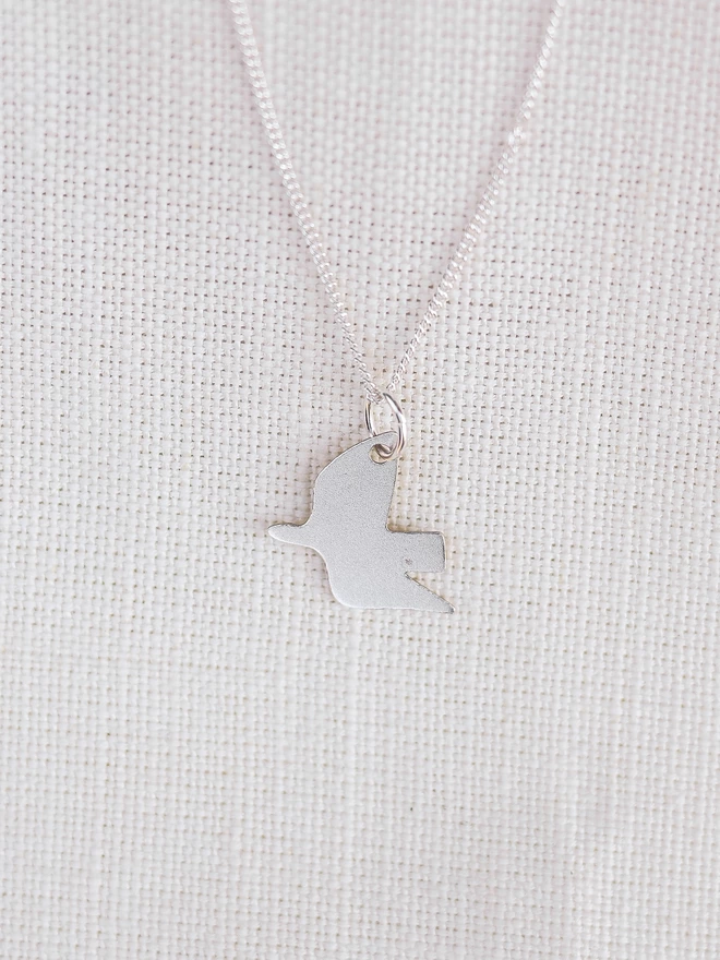 Sterling silver dove pendant necklace on linen material