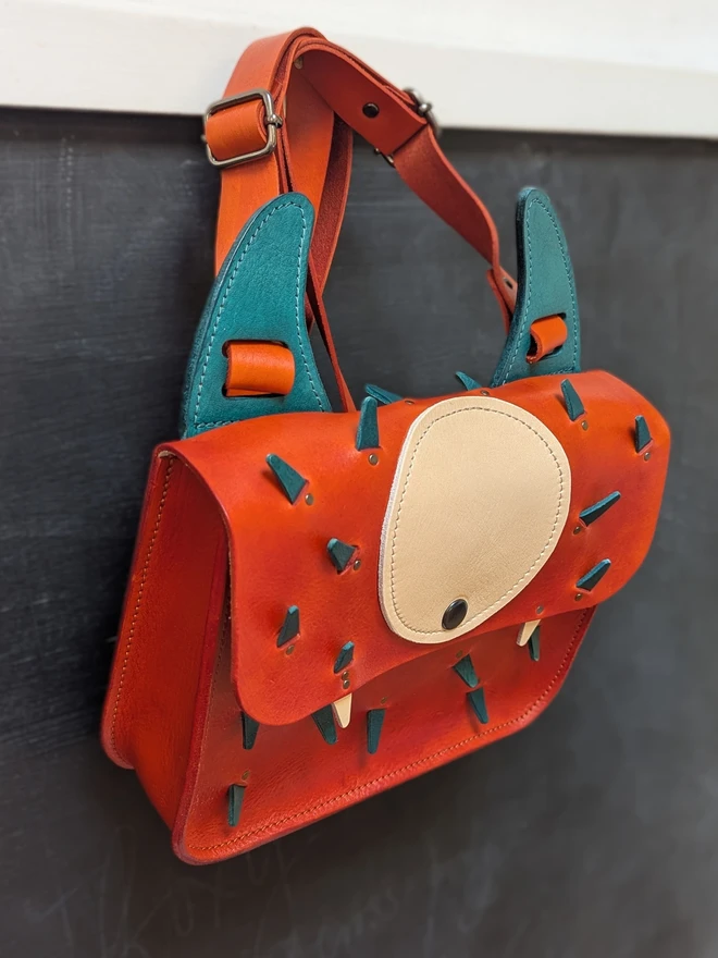 Leather monster backpack in orange and blue left side view