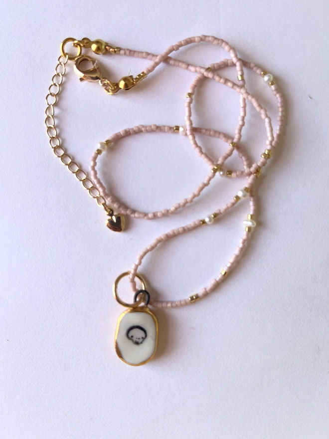 Skull pendant on pink and gold and seed pearl necklace