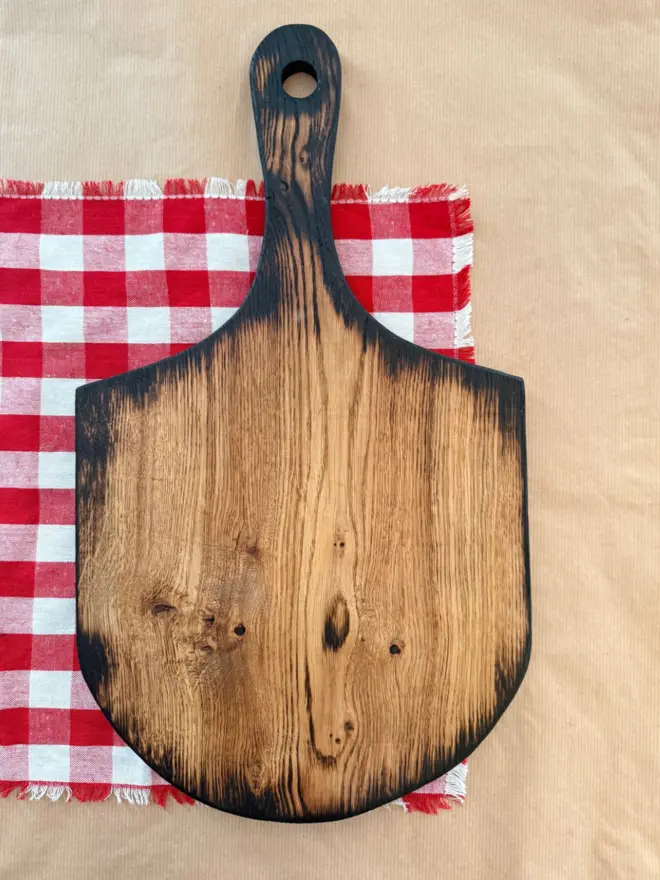 Handmade burnt yakisugi pizza board styled on brown paper with red gingham cloth