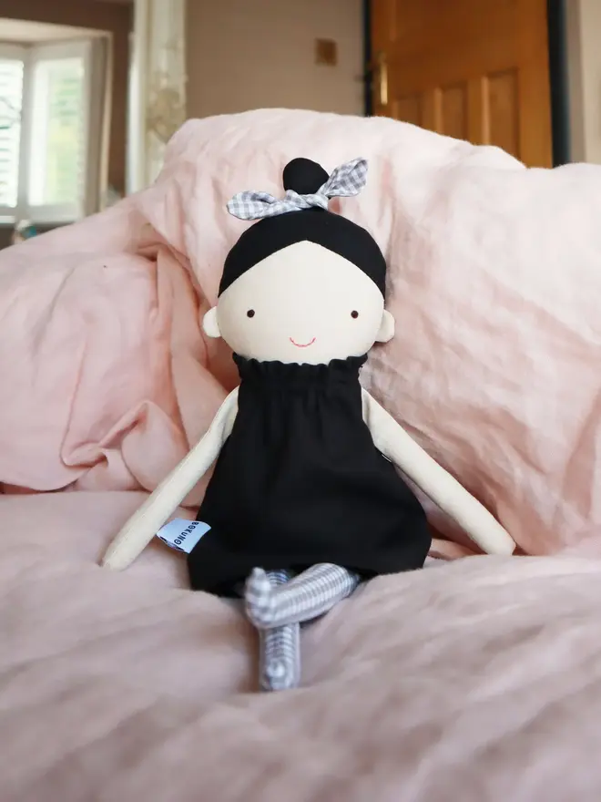 marrie top knot girl doll. a linen doll with a black dress and hair tied up with a grey bow.