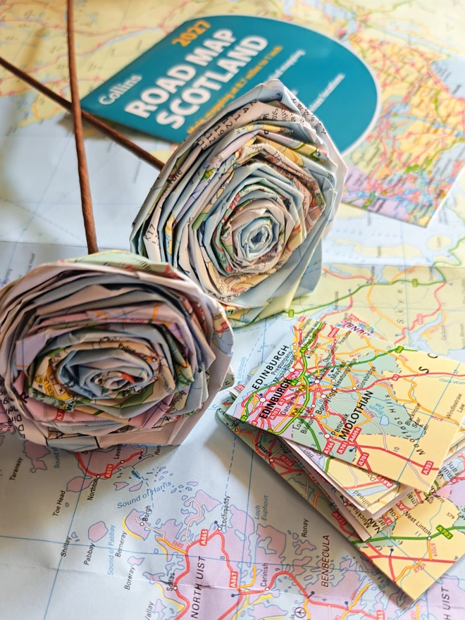Real Paper Map Roses - Custom Destination. a bouquet of paper roses made from old maps, photographed on top of other maps.