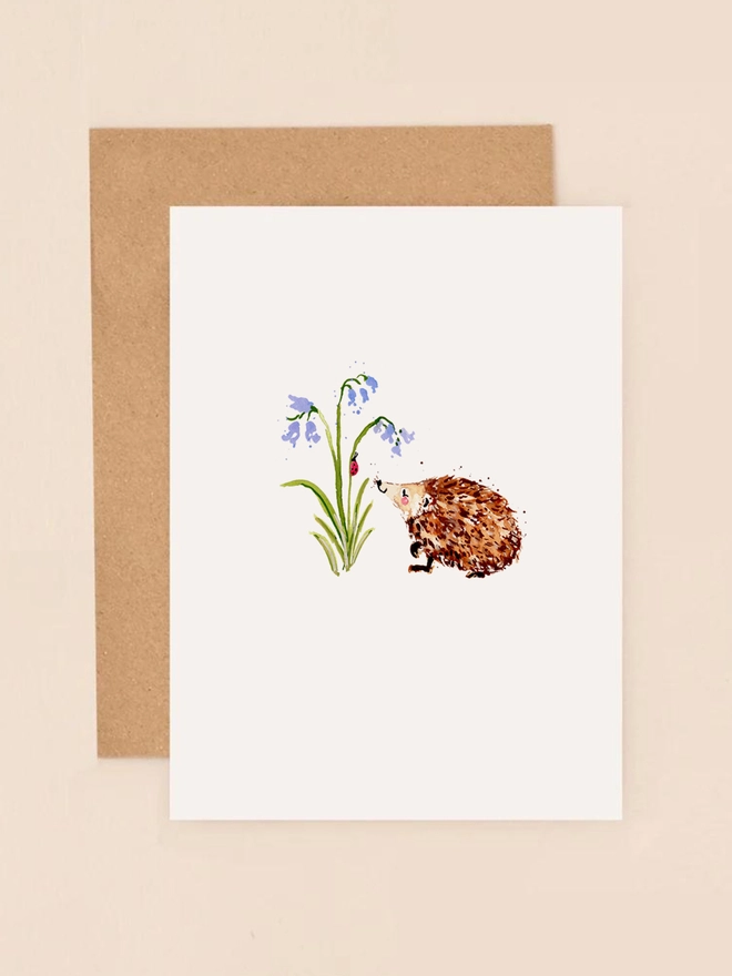 A charming illustration of a small hedgehog nestled among delicate bluebell flowers, capturing the essence of spring. The hedgehog's spiky fur and the bell-shaped blooms are rendered in soft, pastel hues, creating a serene and nature-inspired scene. The design is minimalist and heartwarming, perfect for conveying a message of kindness or appreciation.