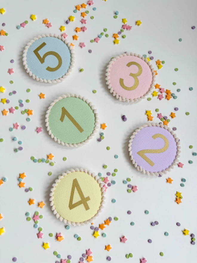 Pastel colour birthday number badges with a pompom trim 