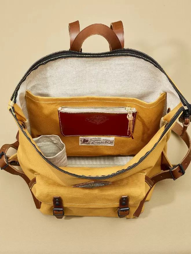 The inside view of the Shortwood backpack in Colemans yellow. With water bottle pocket, large organiser pocket and leather essentials pocket.
