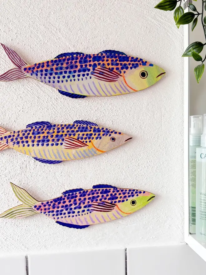 blue wooden mackerel wall decorations. wooden mackerel decorations hung on plain white wall.