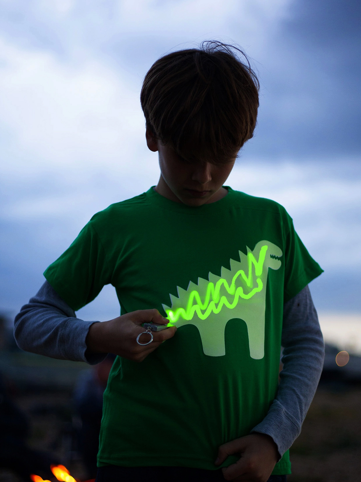 Boy drawing on a glow in the dark dinosaur tshirt