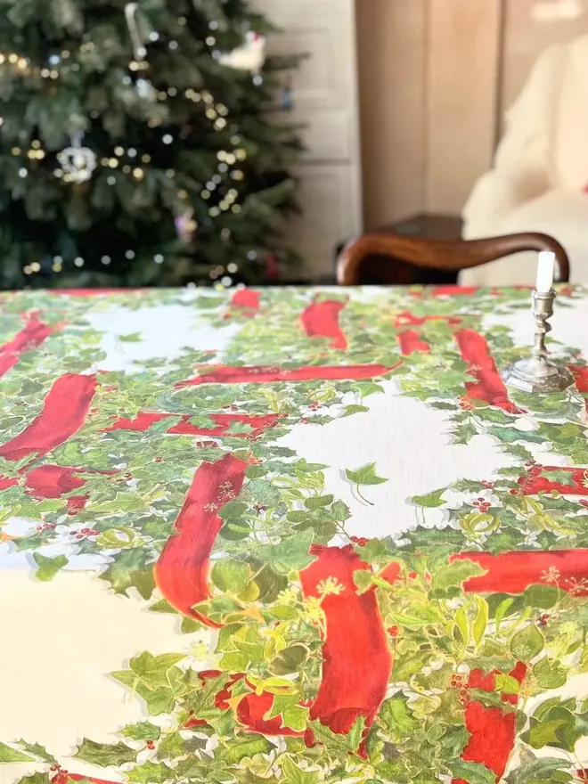 christmas garland lattice tablecloth. a tablecloth printed with holly, ivy and mistletoe on a table.