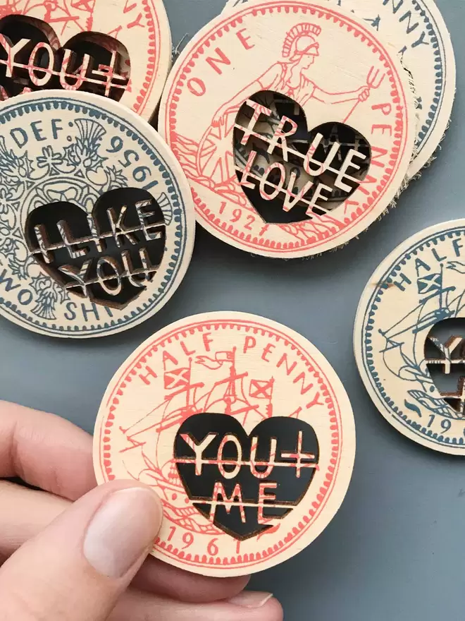 Fiona Biddington holds a friendship screenprinted and laser cut love token that reads 'you + me’