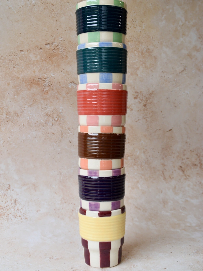     Stack of colourful striped ceramic tumblers