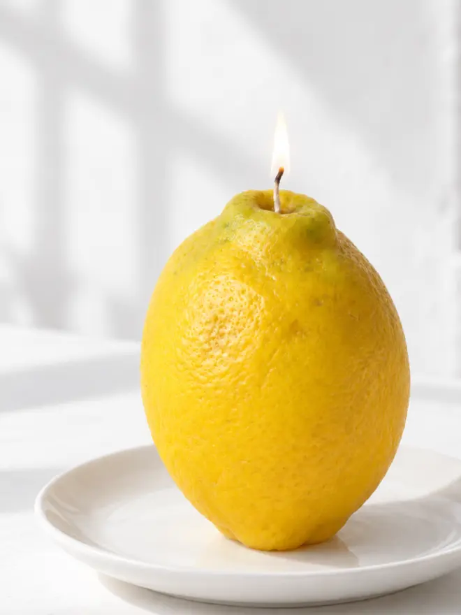 large eureka lemon on a plate, small flame on the wick