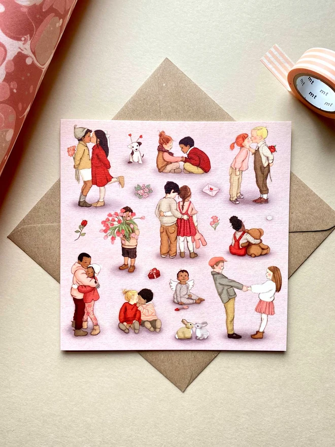 a phot of a valentines greeting card featuring sweet drawings of vintage style children's book illustrations of children hugging and cuddling laid on a Kraft envelope