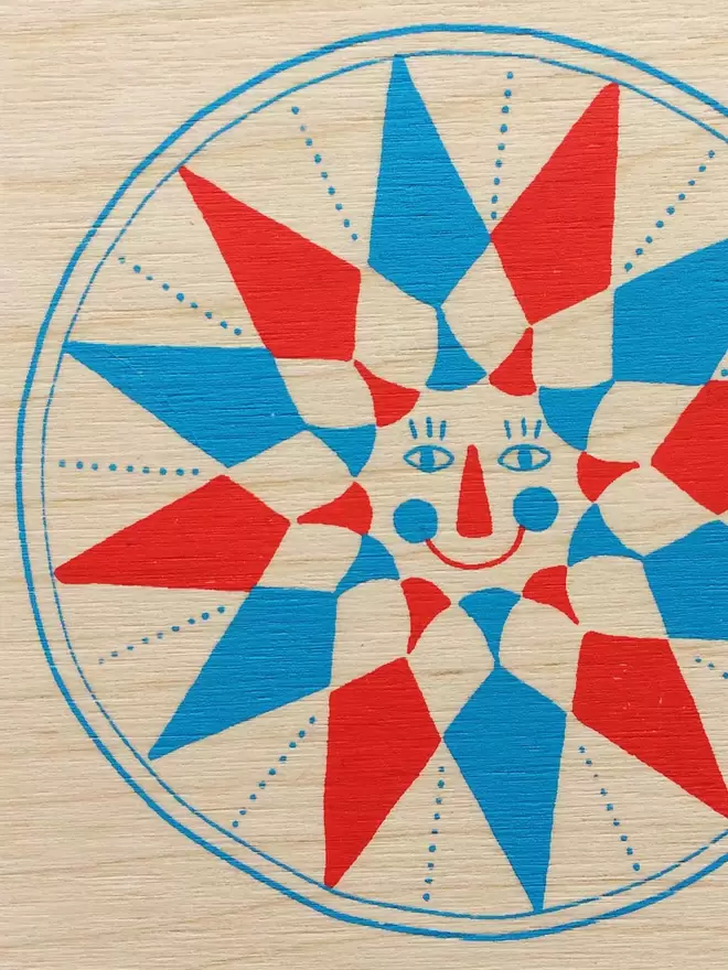 A close up of one of the smiling, screen printed wooden stars, in blue and red ink