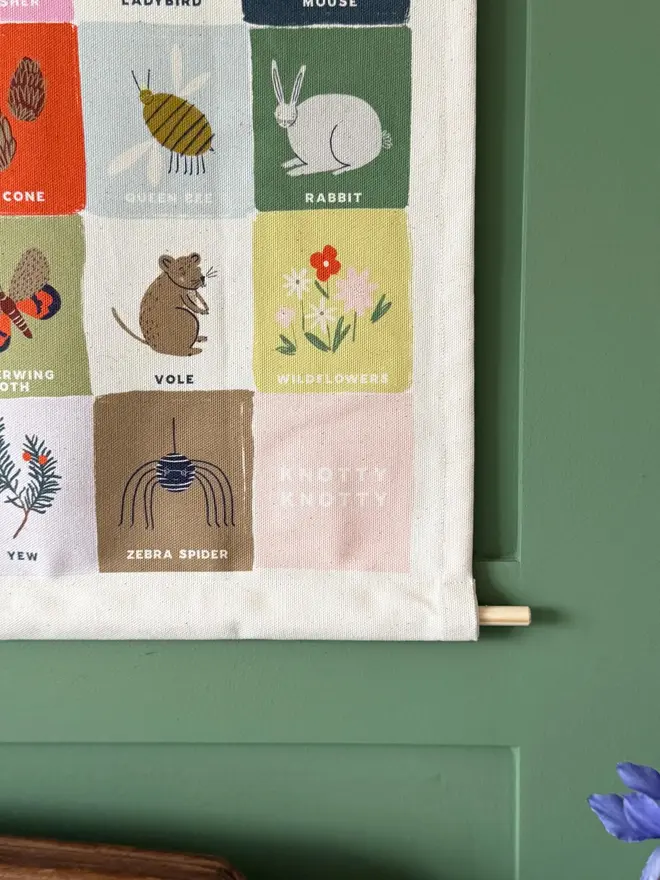 Rainbow Woodland Alphabet Fabric Banner, hanging in a green wall. 