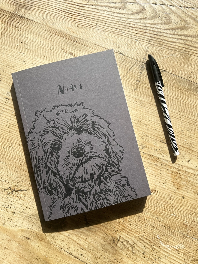 Cockapoo puppy note book with a pen next to it.