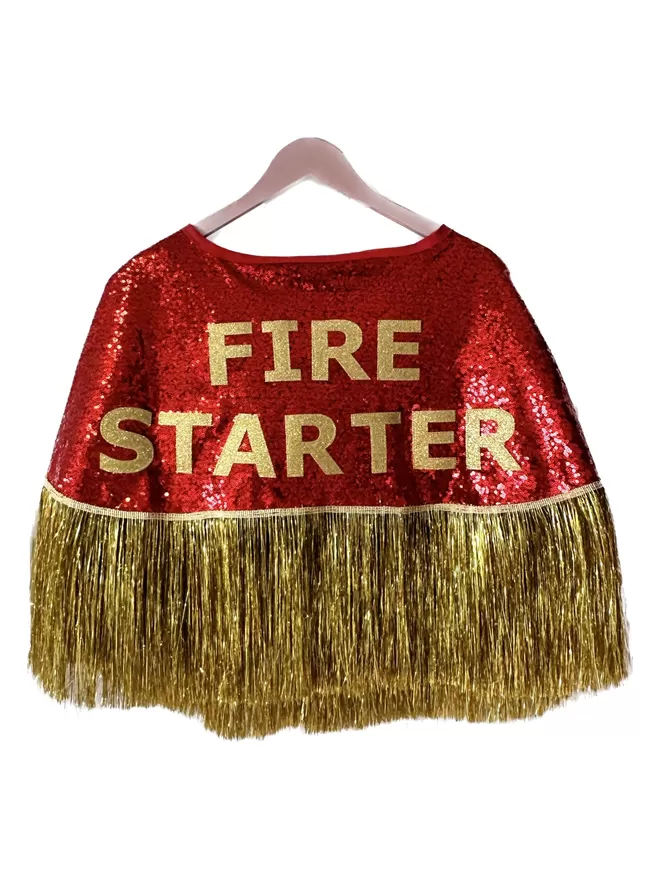 a midi cape with red sequins, gold text reading 'FIRE STARTER' and gold tinsel