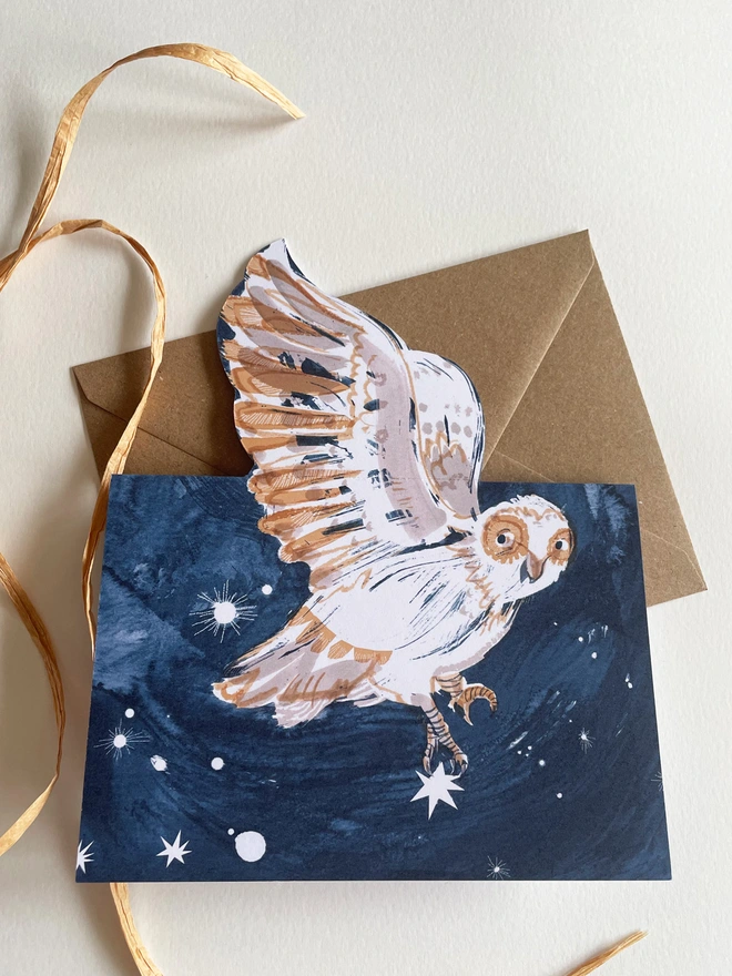 Esther Kent Night Owl illustrated greetings card shows a painterly white and brown owl on a dark blue sky. The wing folds out..