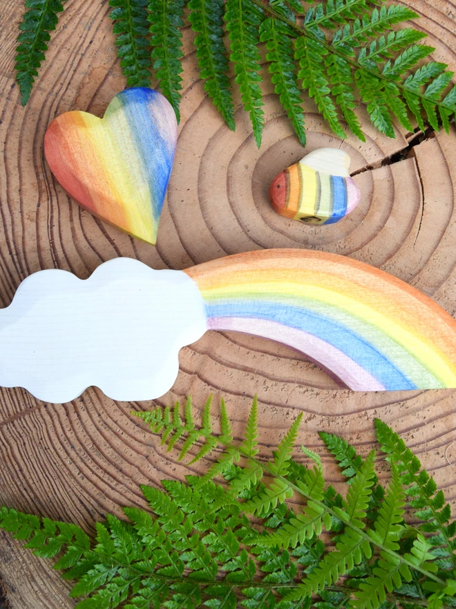 rainbow wooden toys on wood slice with ferns