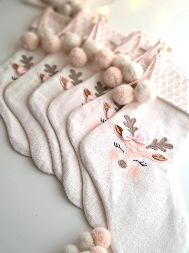 Child's pink and white linen Christmas stocking collection, a group of stockings with felt applique baby reindeer face .