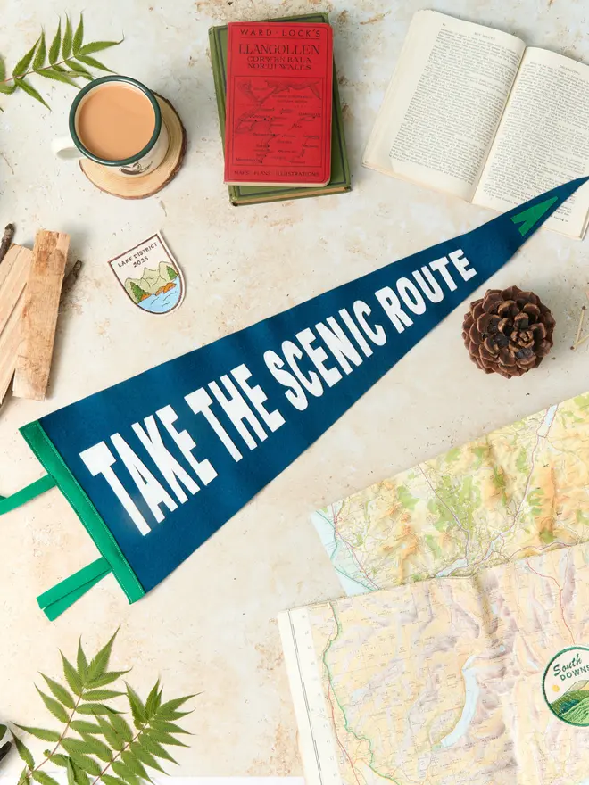 Take the scenic route pennant flag in navy and white laying next to old maps and books