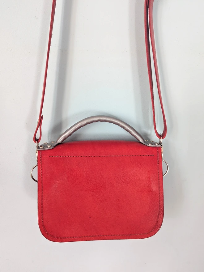 Hanging red leather robot cross body bag, back view.