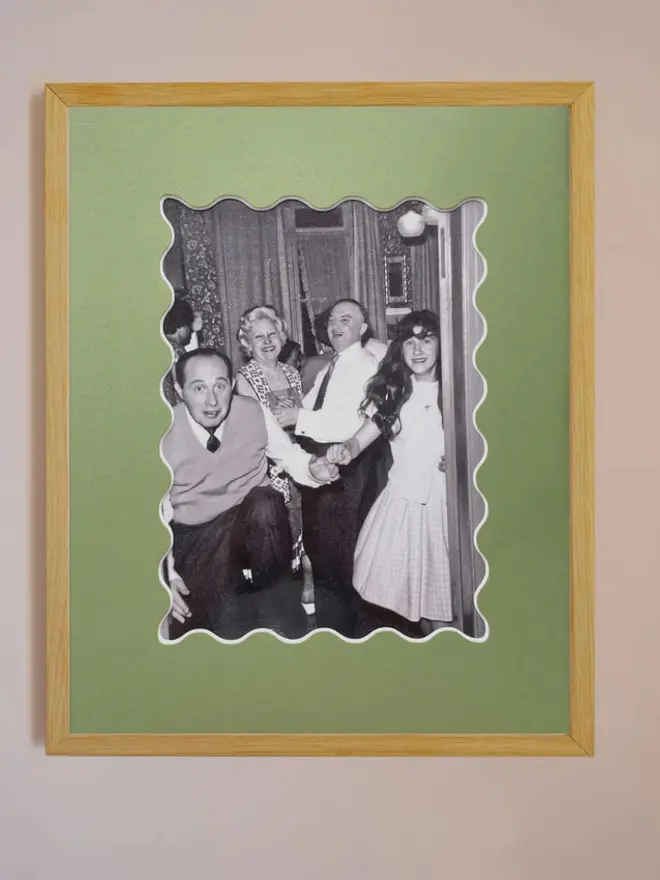 Ric rac photo mount frame with a green mount featuring a decorative ric rac boarder around a centered Instax photo, displayed on a neutral beige wall.