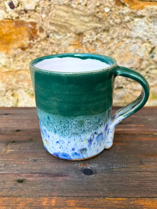 Shoreline Standard Mug, a colourful mug placed on a wooden surface. 