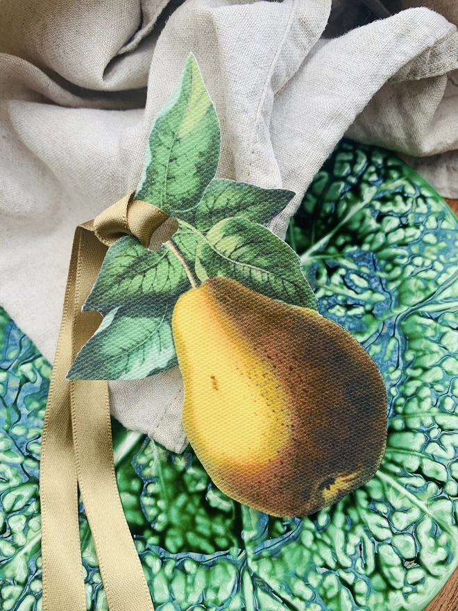 A golden pear with satin ribbon for tying around a napkin for place settings