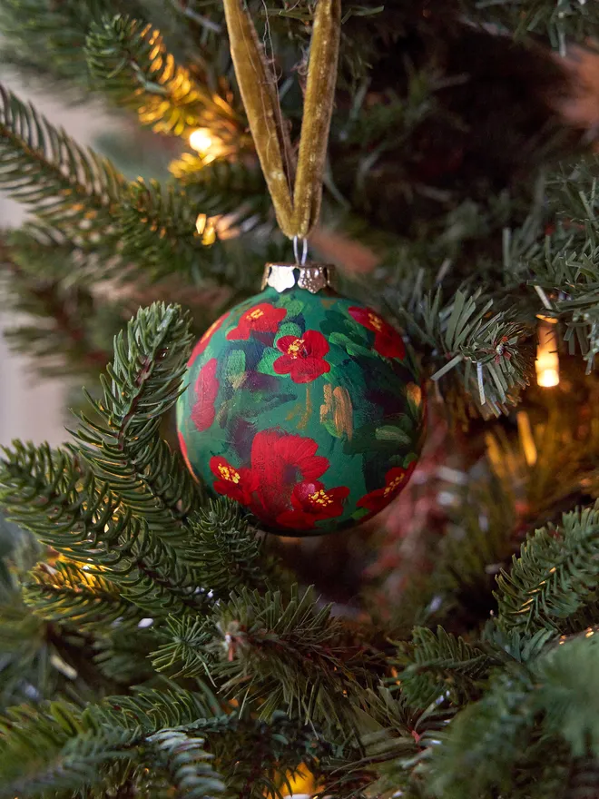 Unique hand-painted ceramic floral bauble featuring red quince flowers on a deep green background