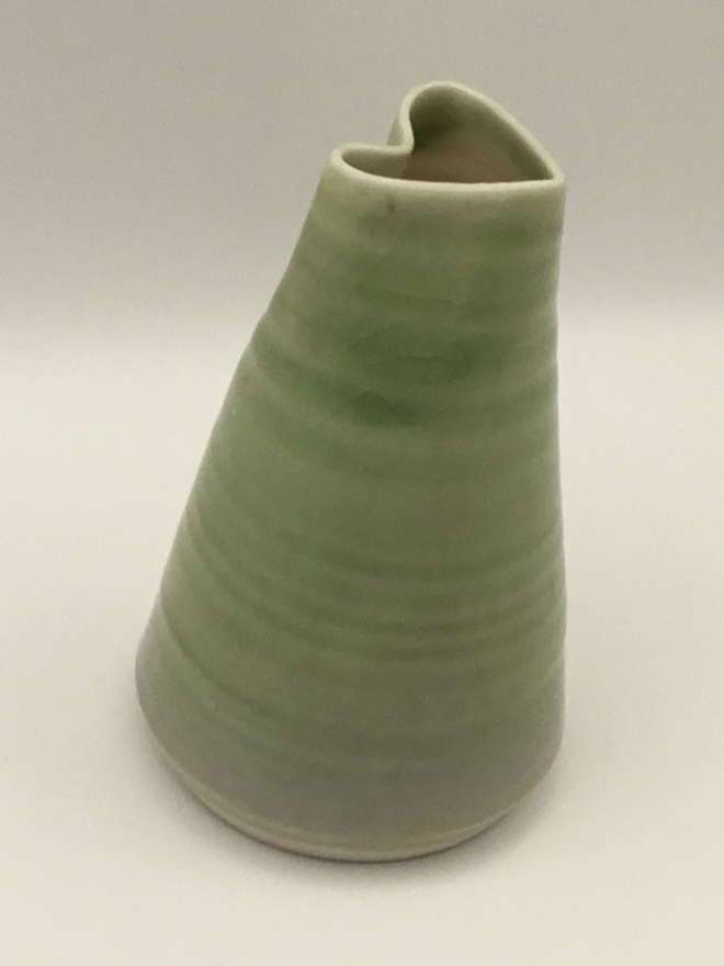 porcelain heart shaped green bud vase. a studio image of a green bud vase with a heart shaped opening, photographed against a white backdrop.