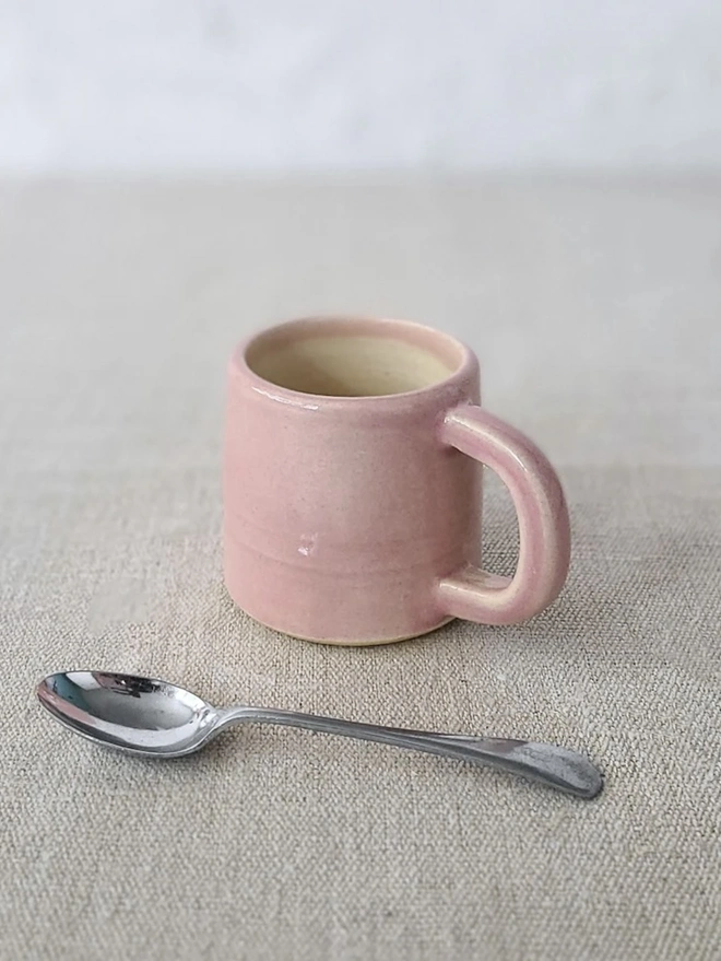 Classic Ceramic Espresso Mug, a colourful ceramic espresso mug sitting on a plain surface against a white backdrop. It is accompanied by a spoon. 