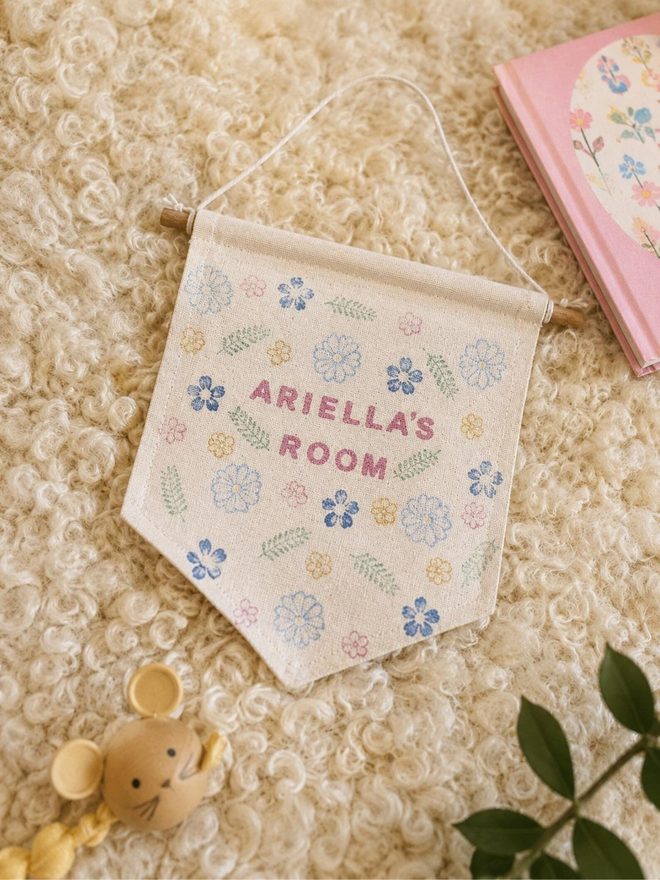 customised kids' bedroom cotton wall hanging. a banner with printed flowers hanging on a bedroom wall.