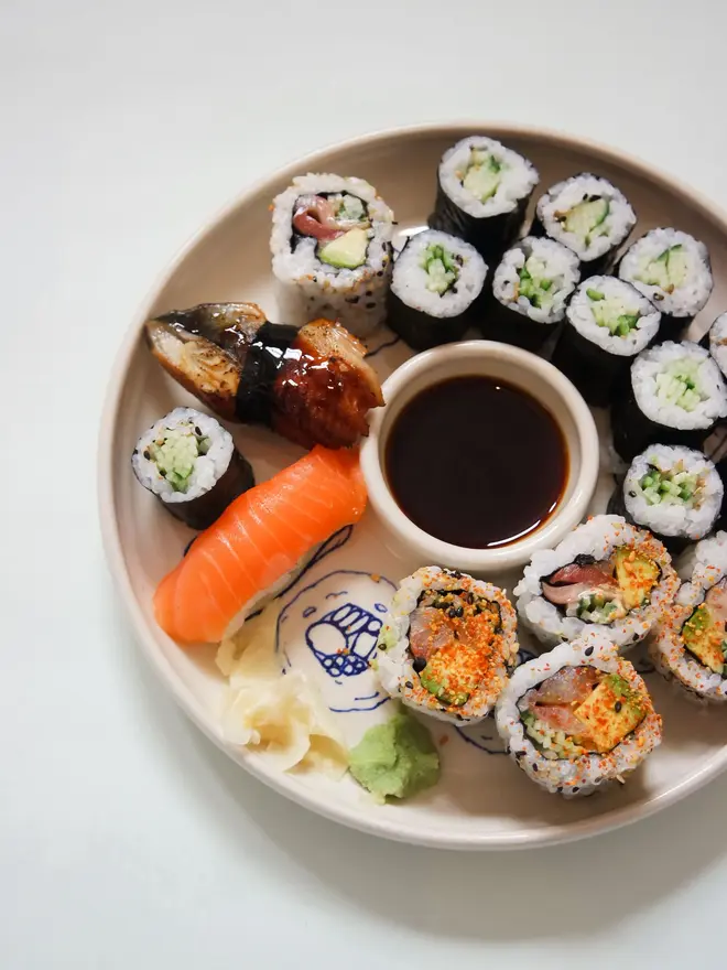 Snack Sushi Dippy Plate, a sushi snack dish sitting on a white surface. It is accompanied by sushi. 