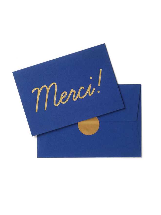 Luxury gold foil Merci thank you type on navy blue card with matching envelope and gold sticker label seal 