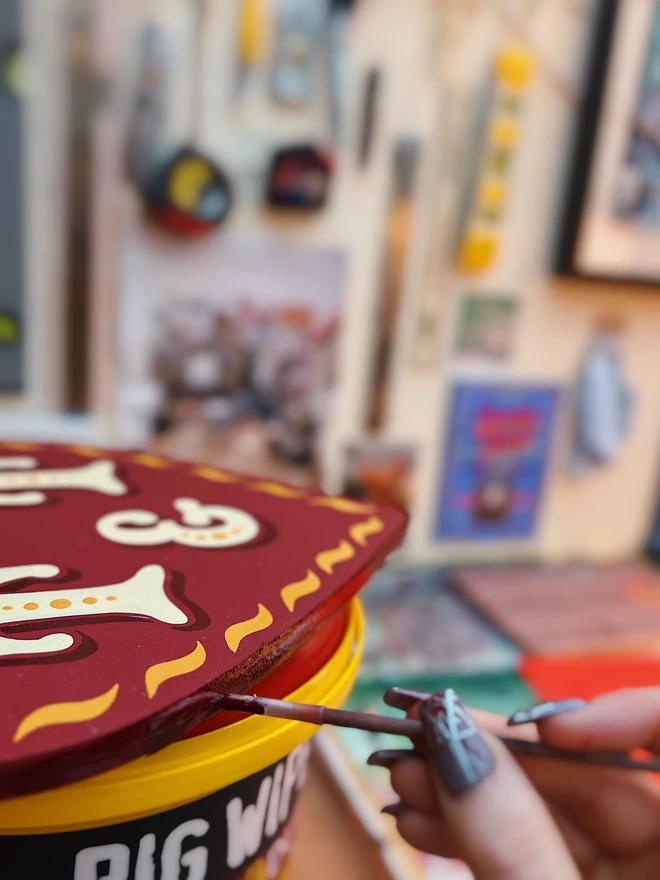 Close up detail shot of the heart shaped edge being hand-painted with a deep red glossy enamel.