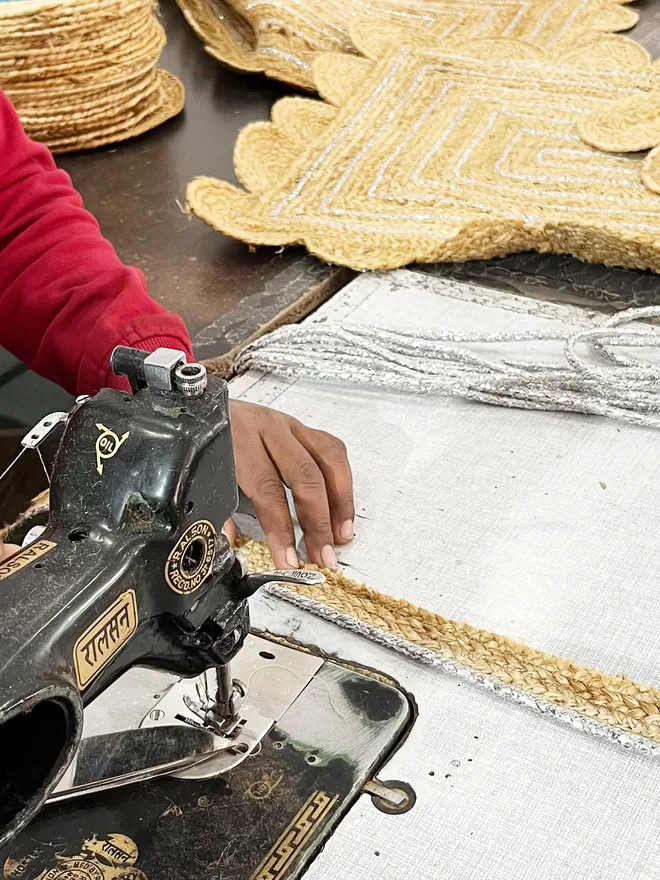 Detail of sewing machine and silver trim being attached to a braided jute tape